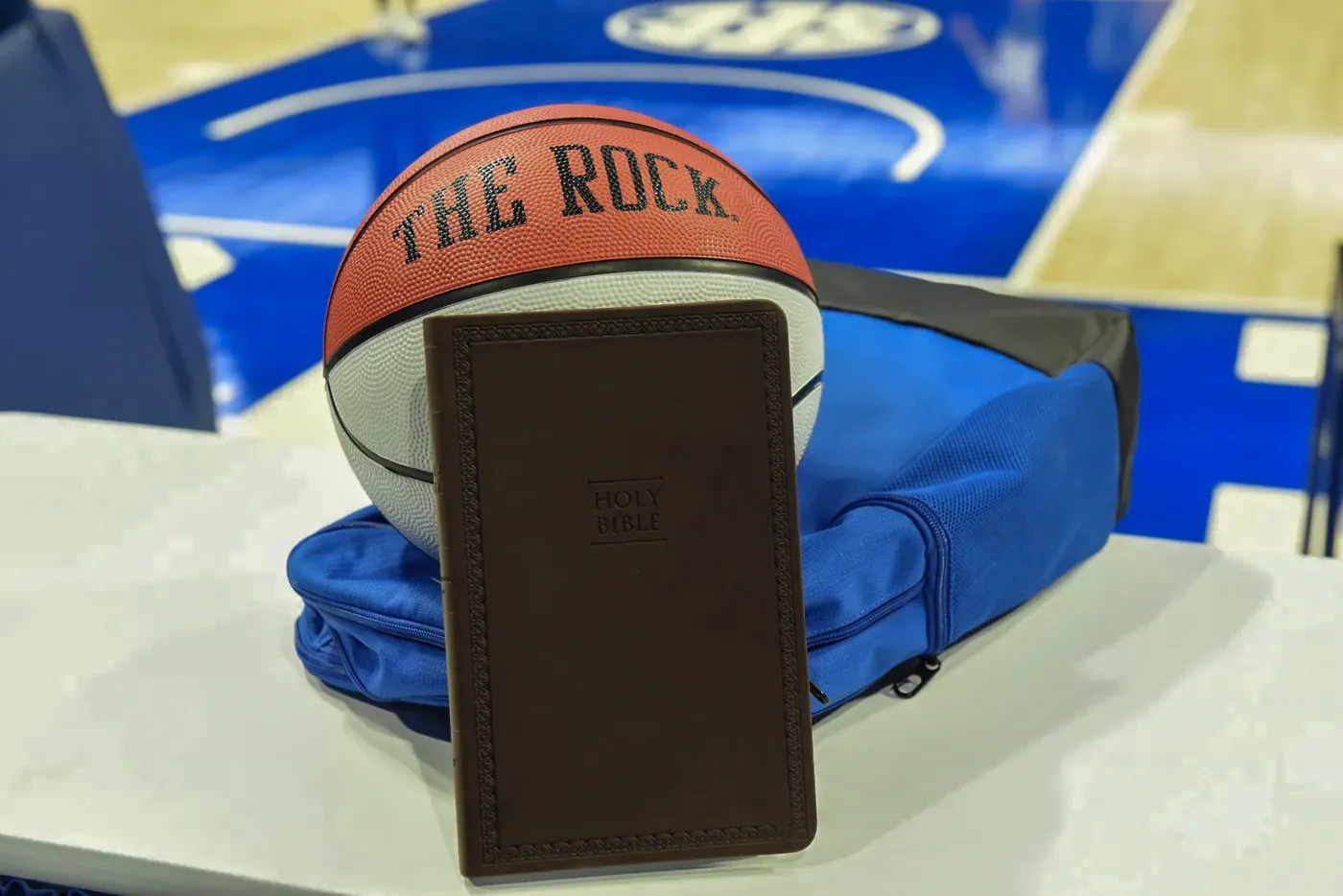 A basketball resting beside a Holy Bible on the court